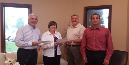 DEHCO CFO, Brent Jagla (second from right) and Accretive of Indiana’s Bill McDonough (left), present initial “shared savings” checks for the pledged $30,000 to Shelley Lesniewicz, Executive  Director of Ronald McDonald House Charities of Michiana.  Chris White, DEHCO Controller, is on the right